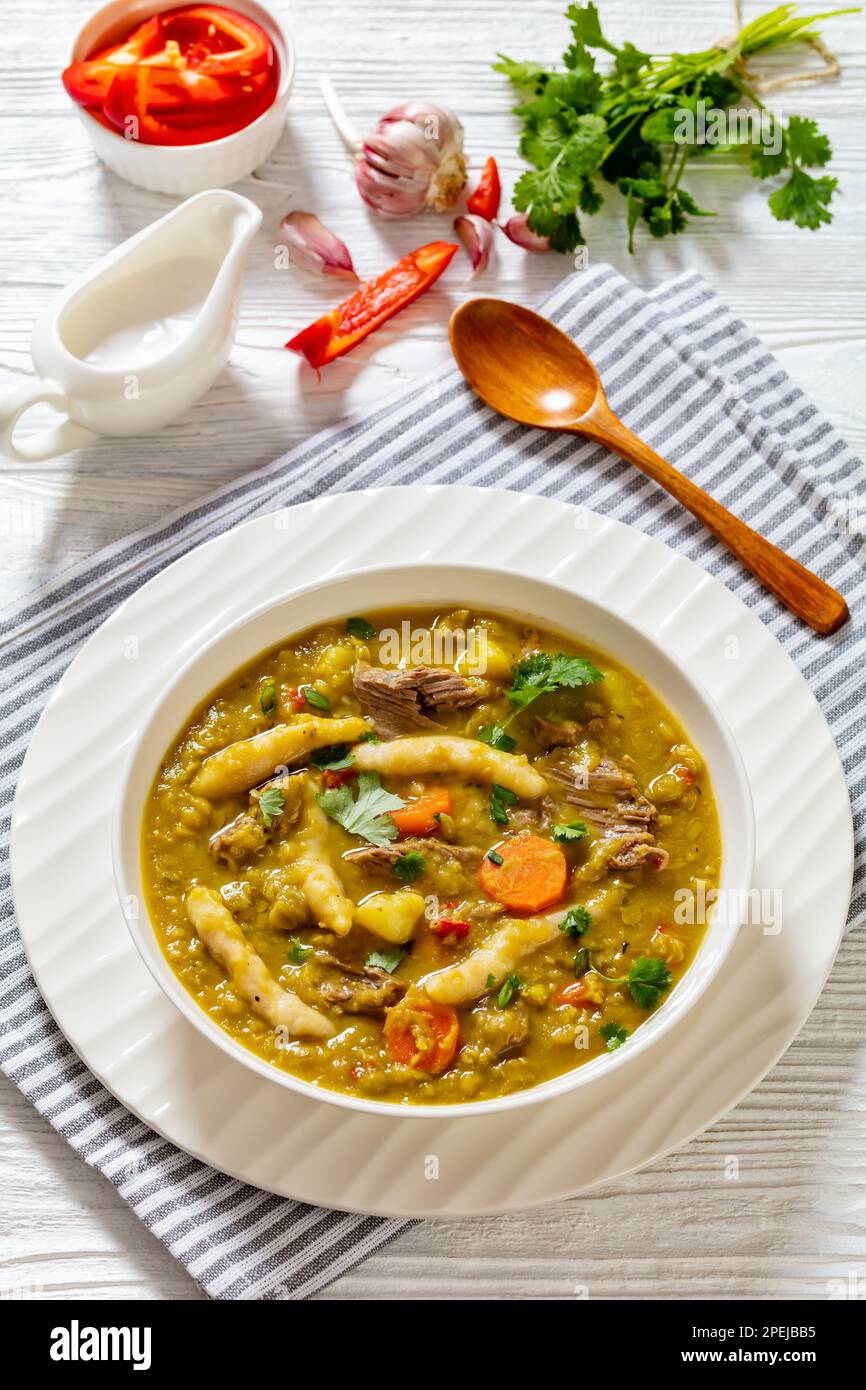 petits pois, soupe de petits pois avec boulettes, légumes et bœuf dans un bol blanc sur table blanche, cuisine jamaïcaine, vue verticale Banque D'Images