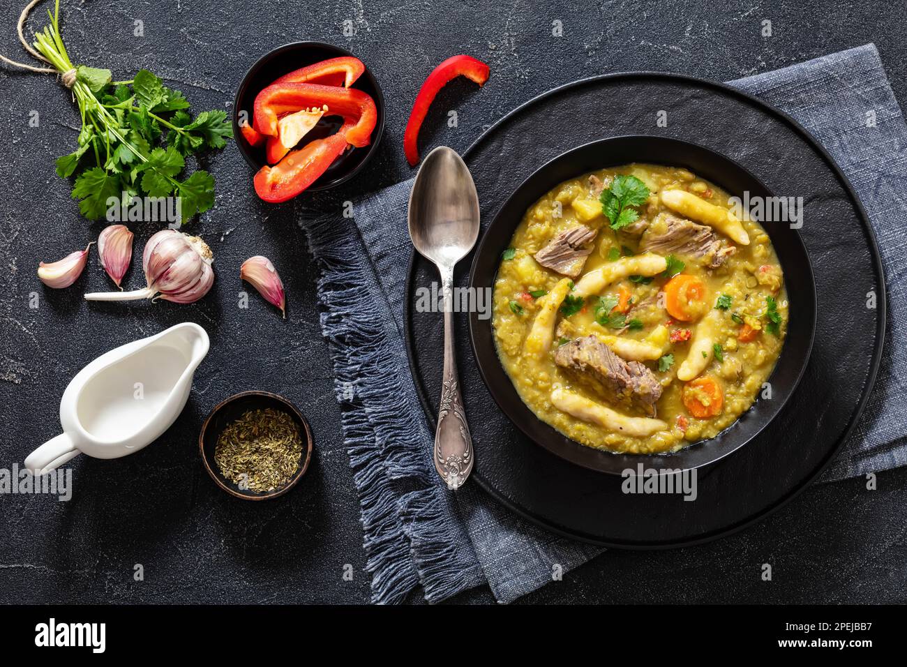 petits pois, soupe de petits pois avec boulettes et bœuf dans un bol noir sur table en béton avec ingrédients, cuisine jamaïcaine, vue horizontale d'en haut, f Banque D'Images
