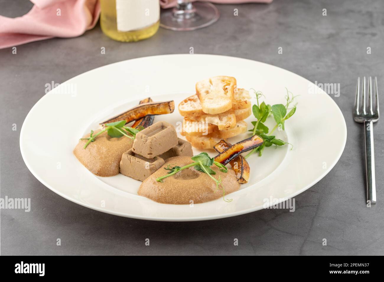 Foie gras de canard à la sauce et pain croustillant sur une assiette en porcelaine blanche Banque D'Images