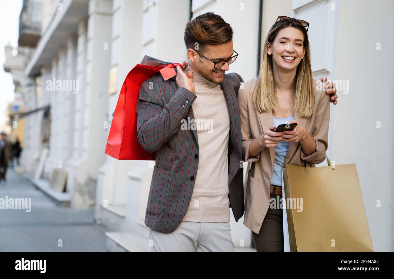 Beau jeune couple aimant portant des sacs d'achats et appréciant le temps ensemble. Banque D'Images