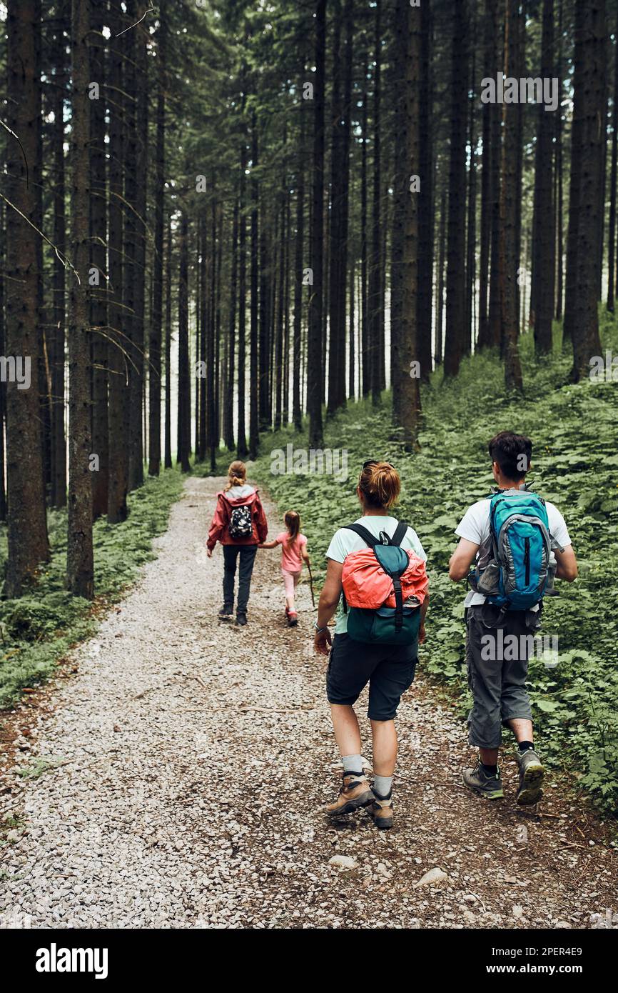 Famille avec sacs à dos randonnée dans une montagne passer des vacances d'été ensemble en marchant sur un chemin forestier. Des personnes actives passent du temps à l'extérieur Banque D'Images