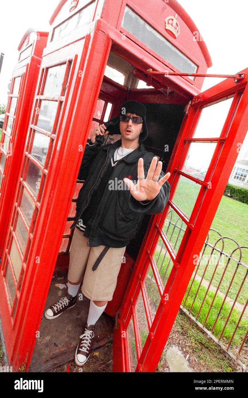 Jeune homme dans une boîte téléphonique britannique - Brighton & Hove, East Sussex, Royaume-Uni Banque D'Images