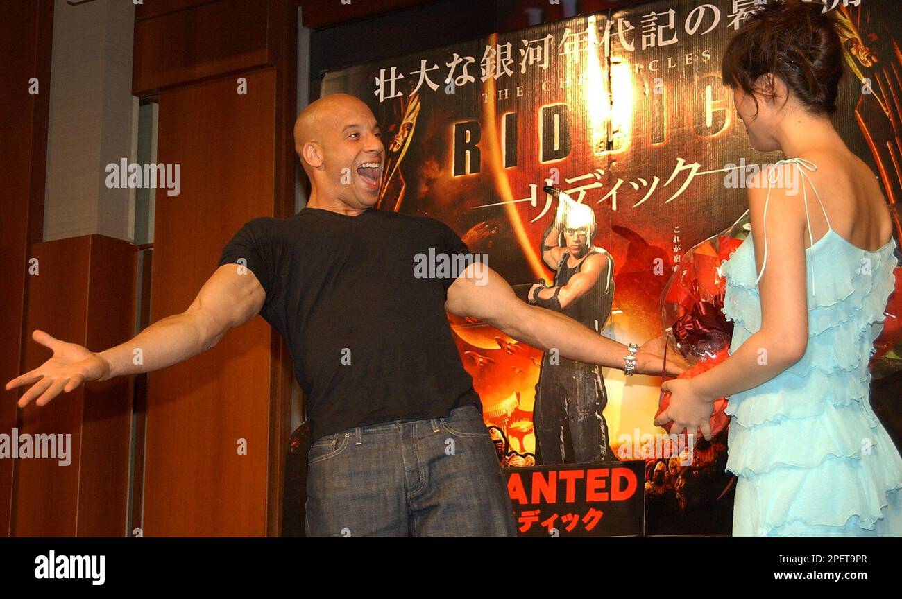 Hollywood actor Vin Diesel, left, reacts as Japanese model Kasumi Nakane greets him with a bouquet of flowers during a press conferece in Tokyo, promoting his sci-fi saga film "The Chronicles of Riddick" Friday, July 30, 2004. The action movie will be released in Japan Aug. 7. Nakane played the voice of the film heroin Kyra in the dubbed Japanese version. (AP Photo/Katsumi Kasahara) Banque D'Images