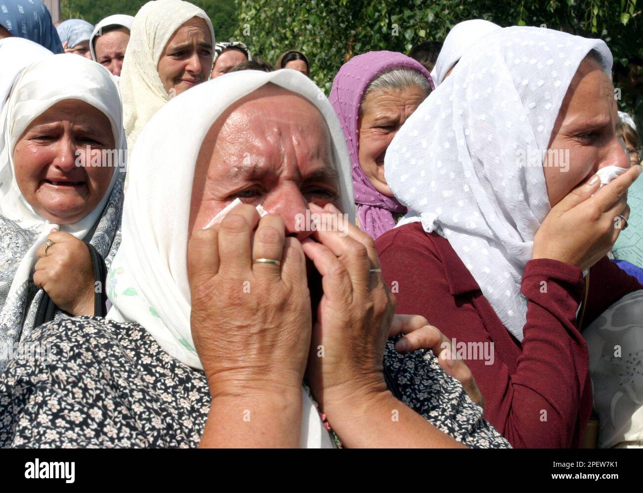 Bosnian-Muslim women cry as a convoy with 335 bodies leaves a morgue in the central Bosnian town of Visoko on its way to Srebrenica on Friday, July 9, 2004. The 335 bodies were excavated from mass-grave sites in Eastern Bosnia and were identified as Muslims killed by Bosnian-Serb forces in the area of Srebrenica. The bodies are transported to a memorial center in Potocari near Srebrenica where they will be burried on July 11, 2004. (AP Photo/Hidajet Delic) Banque D'Images