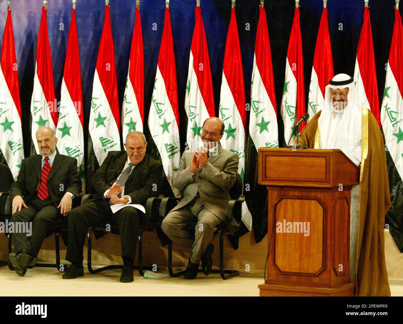Iraqi President Ghazi Al-Yawer, far right, delivers a speech as members of the government applaud in front of a row of Saddam Hussein-era Iraq national flags at a swearing in ceremony in Baghdad, Iraq, Monday June 28, 2004. From left are Vice President of Iraq Ibrahim Al-Jaafari , Prime Minister Ayad Allawi, and Deputy Prime Minister Barham Salih. (AP Photo/David Guttenfelder) Banque D'Images
