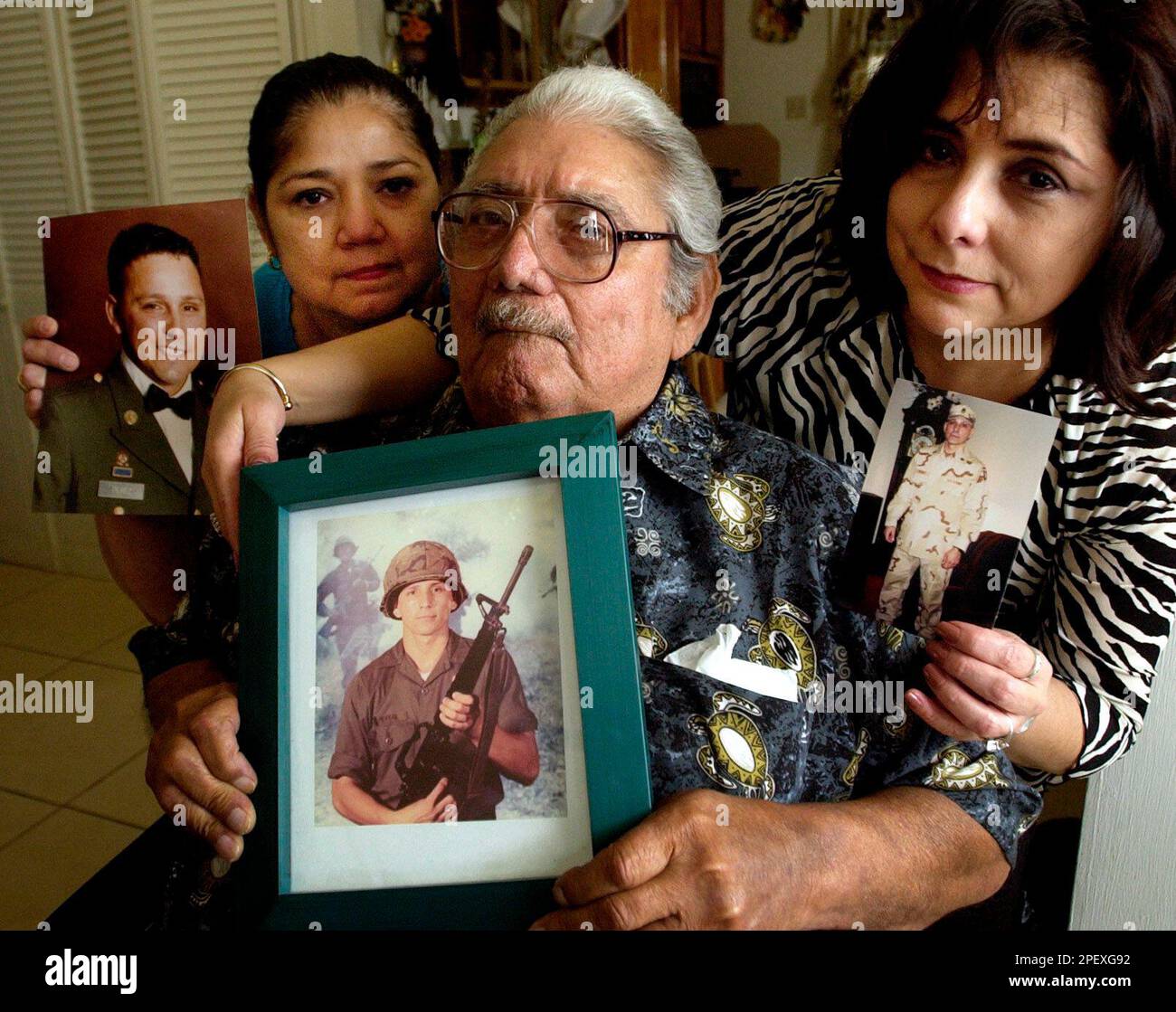 ** ADVANCE FOR SUNDAY, JUNE 20 **World War II veteran Esequiel Perez, center, and two of his daughters, Sandra Vasquez, left, and Yolanda Rodriguez, hold photos of son and brother, Staff Sgt. Hector Perez, at their home in Corpus Christi, Texas, May 28, 2004. Hector Perez, Company A, 1st Battalion, 327th Infantry, 101st Airborne Division from Fort Campbell, Ky., was killed in Iraq when his convoy was ambushed. (AP Photo/Eric Gay) Banque D'Images