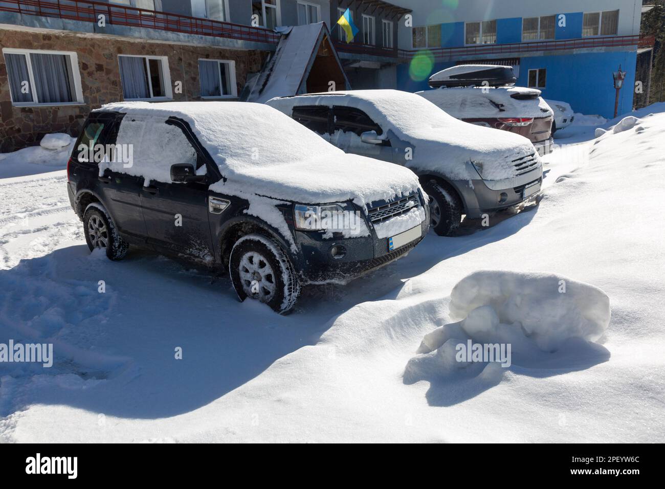 Voitures couvertes de neige dans le parking en face de l'hôtel ukrainien, SUV dans la neige dans les montagnes Banque D'Images