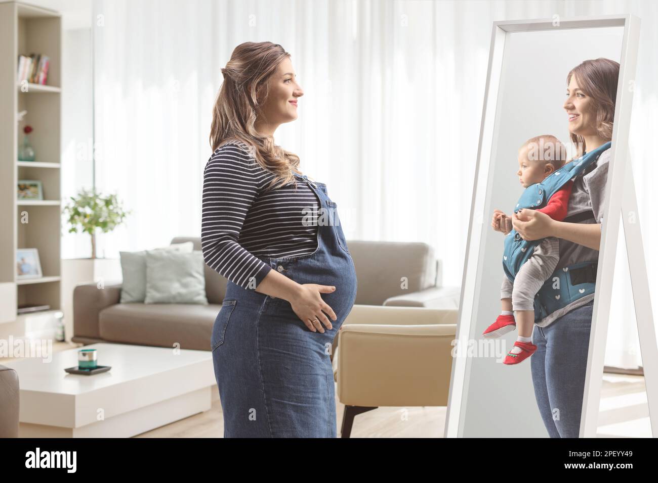 Femme enceinte se regardant elle-même un miroir tenant un bébé à la maison  dans un salon Photo Stock - Alamy