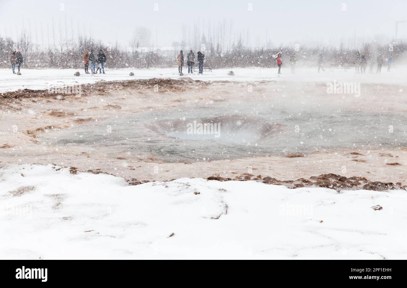 Les touristes attendent une éruption geyser dans le sud-ouest de l'Islande lors d'une journée d'hiver enneigée Banque D'Images