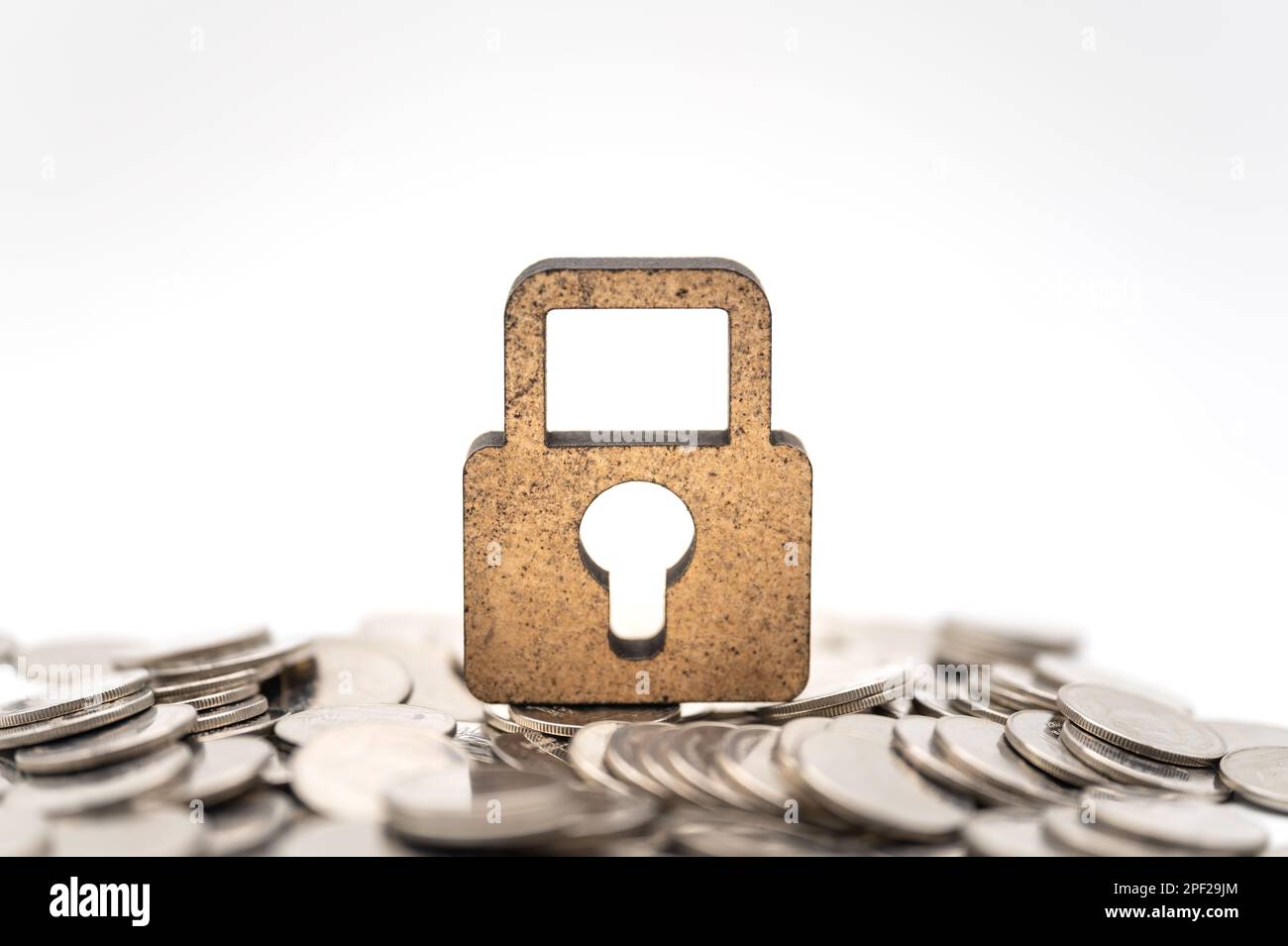 Concept argent et sécurité. Icône de serrure principale en bois sur pile de pièces sur fond blanc. Banque D'Images