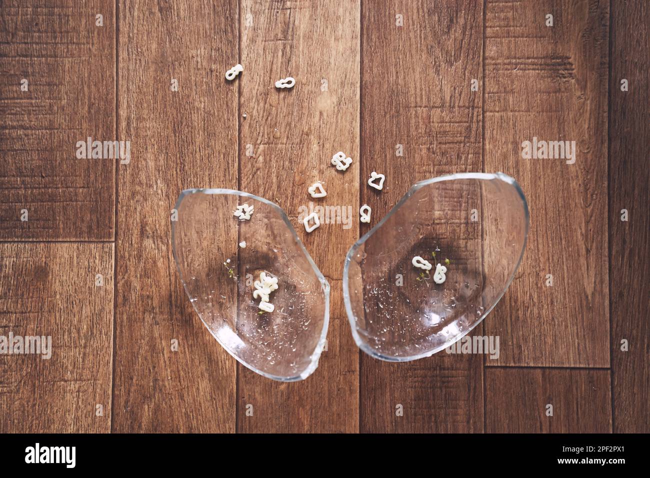 La plaque transparente est divisée en deux parties. Une tasse de soupe de nouilles sous forme de chiffres pour le déjeuner est tombée sur le plancher de bois et s'est brisée. Photo de haute qualité Banque D'Images