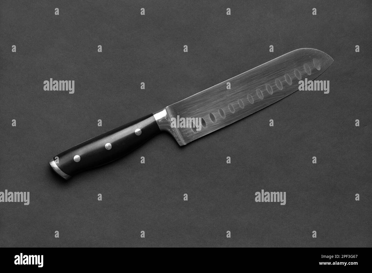 Couteau de cuisine avec poignée noire sur fond noir. Grand couteau sur fond sombre. Ustensiles de cuisine. Couteau à lame large. Banque D'Images