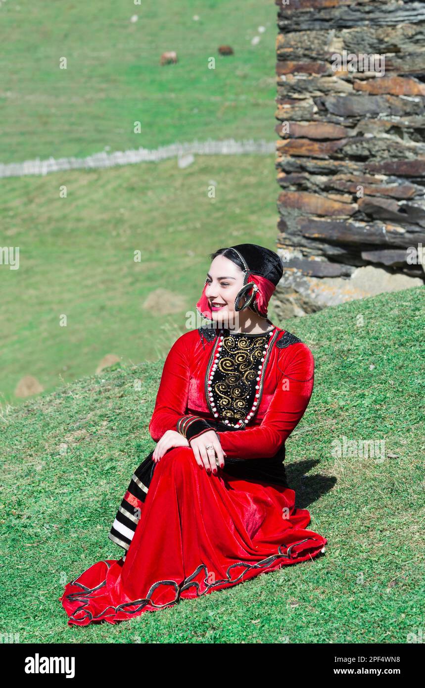 Georgian woman à partir d'un groupe folklorique assis sur le sol en face d'une tour, pour un usage éditorial uniquement, Ushguli, région de Svaneti, Géorgie Banque D'Images