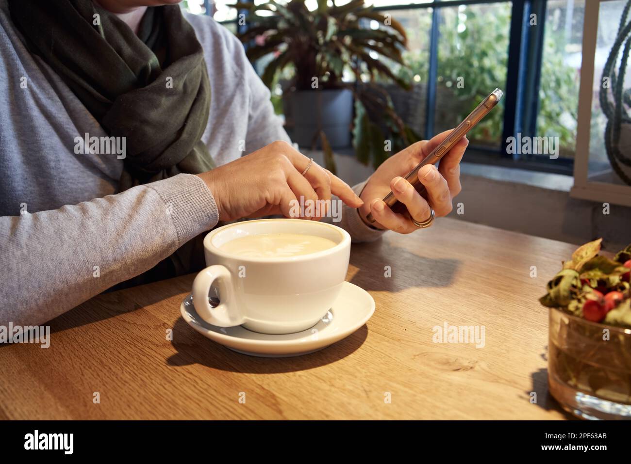 Femme ayant une tasse de café dans un café, tenant un smartphone Banque D'Images