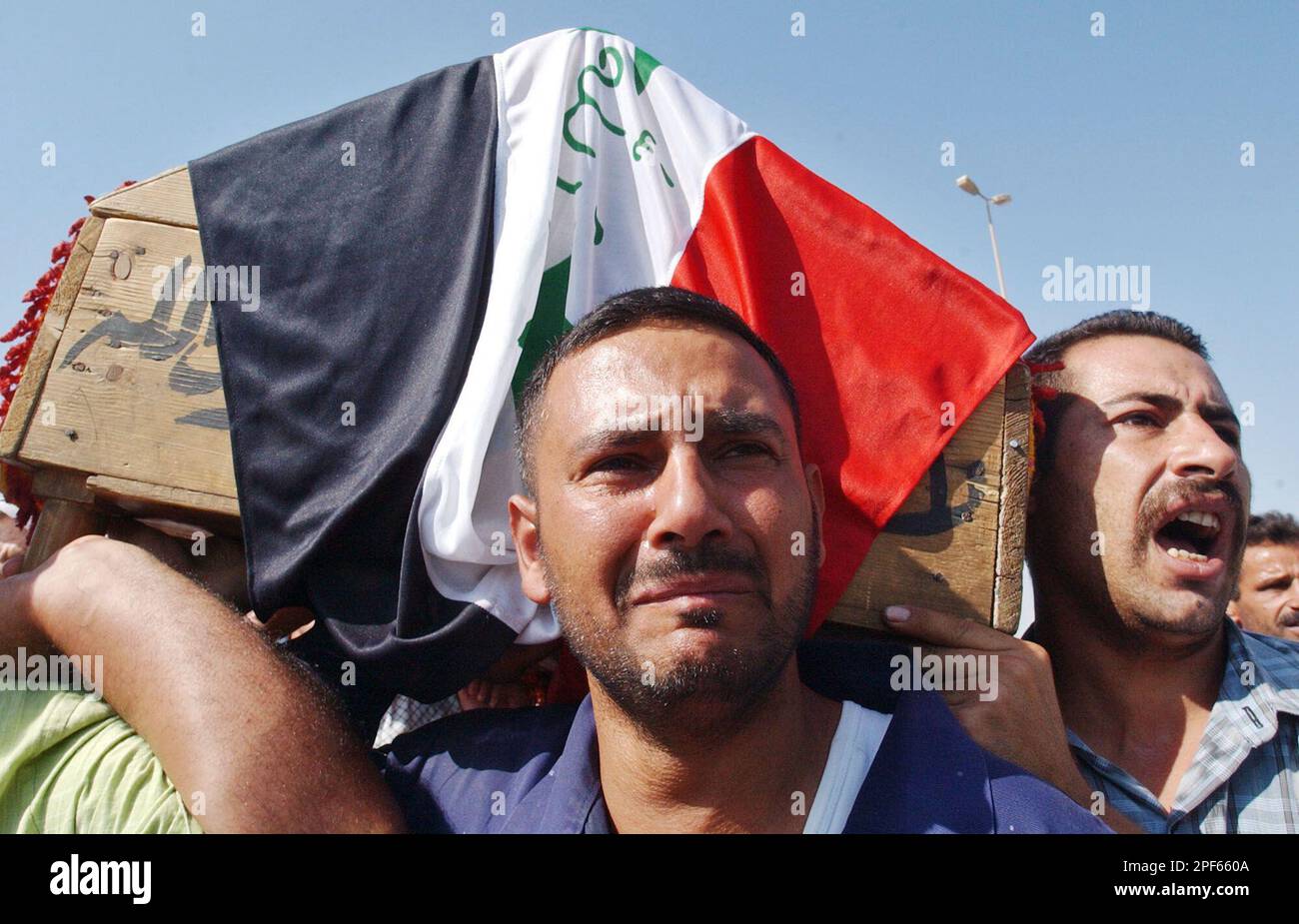 Friends of Odai Ahmad carry his flag-draped coffin during his funeral Thursday July 10, 2003 in Baghdad, Iraq. Odai, 22, was killed Wednesday allegedly by US soldiers manning the roof of a police station while fixing his car behind the building in al-Baya'a. (AP Photo/Ali Haider) Banque D'Images