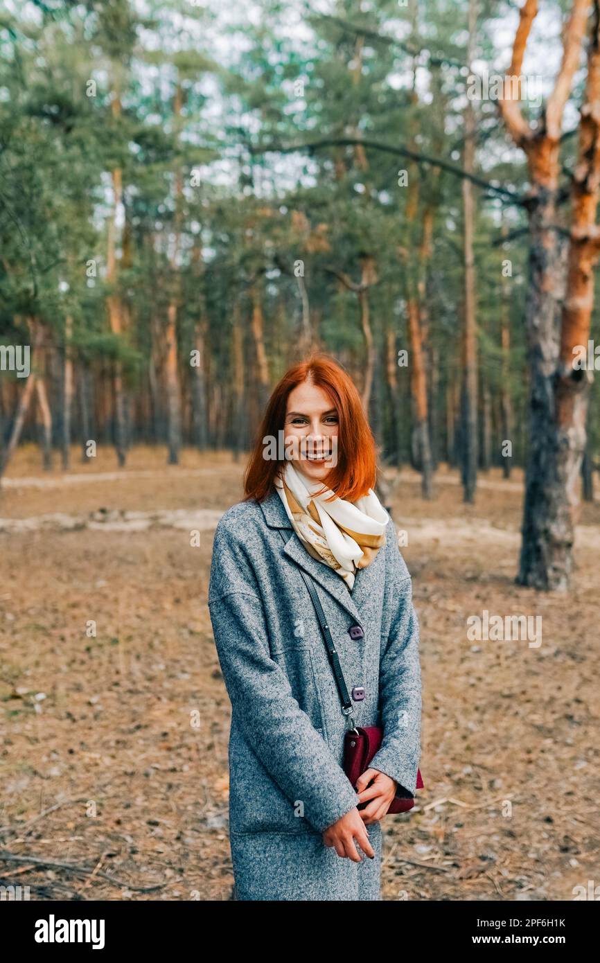 Heureuse belle femme avec des cheveux rouges marchant dans la forêt d'automne. Banque D'Images