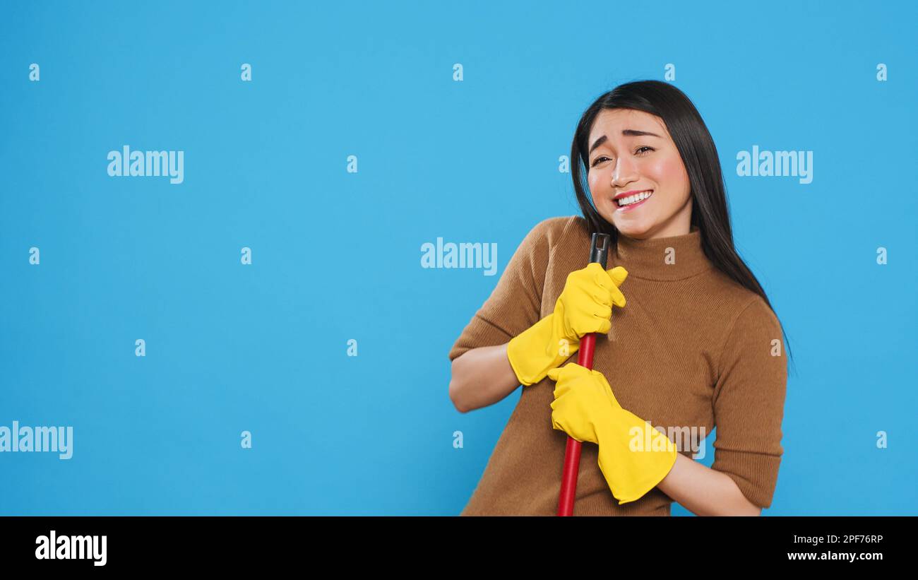 Happy Housekepper dansant et s'amuser en studio tout en faisant le ménage à l'aide d'un balai, dédié à fournir des services de nettoyage de premier ordre à ses clients. Concept d'entretien ménager. Banque D'Images