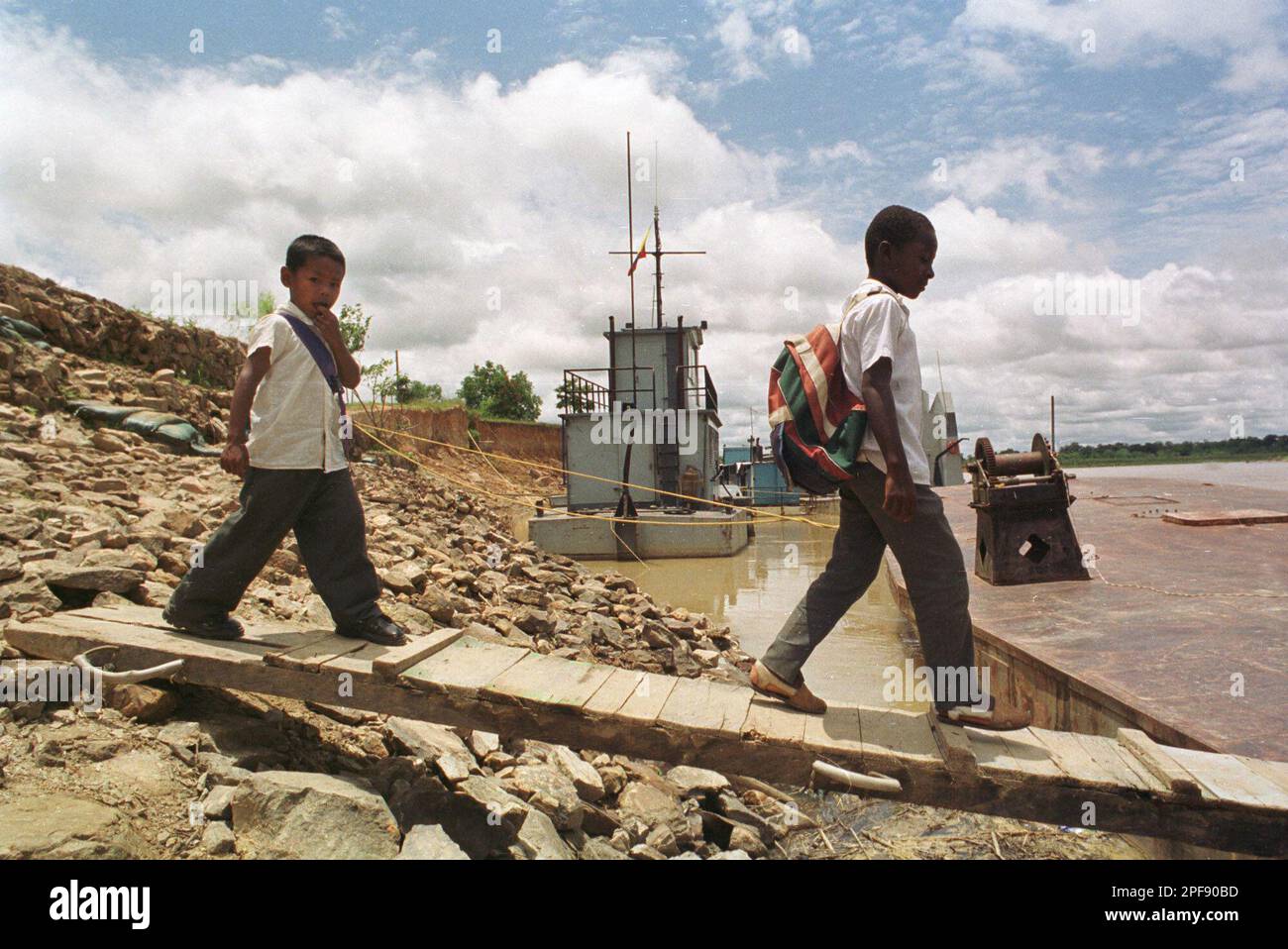 Two students wait for their father to pick them up on a boat along the Guaviare River after attending class at El Barrancon school, near San Jose del Guaviare, in southeastern Colombia, Wednesday Oct. 9, 2002. In the lawless jungles of the state of Guaviare, where coca, the base ingredient of cocaine, reigns, less than half of the children go to school. Of those who do, only 20 percent make it through ninth grade. (AP Photo/Juan Herrera) Banque D'Images