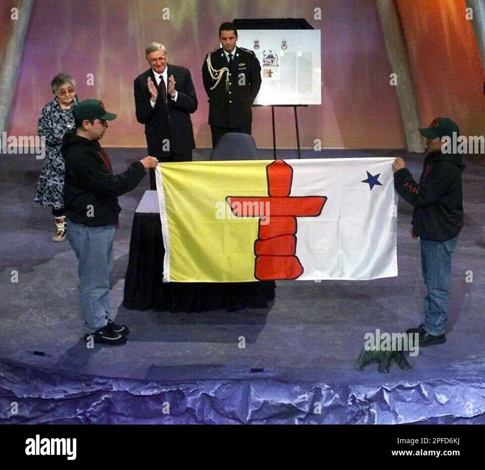 Two Inuit Junior Rangers unveil the new Nunavut flag accompanied by Governor-General Romeo LeBlanc, background center, and Nunavut Commissioner Helen Maksagak, left, during a ceremony in Iqaluit, Nunavut, Canada Thursday, April 1, 1999 celebrating the new territory. Canada redrew its map Thursday and created the new, Inuit-led territory of Nunavut. The region, as big as Western Europe, consists of the eastern 60 percent of the Northwest Territories. The division is the first major change in the map of Canada since Newfoundland joined the nation 50 years ago. (AP Photo/Pool) Banque D'Images