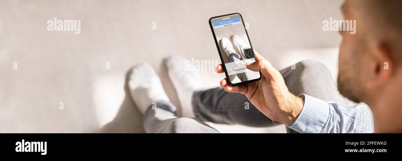 Homme essayant des baskets virtuelles dans Shop ou Store AR App Banque D'Images Homme essayant des baskets virtuelles dans Shop ou Store AR App Banque D'Images