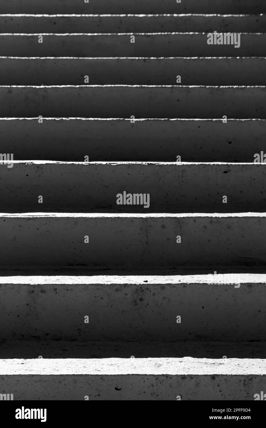 Escaliers en béton avec ombres sombres, arrière-plan architectural vertical abstrait. Photo en noir et blanc Banque D'Images
