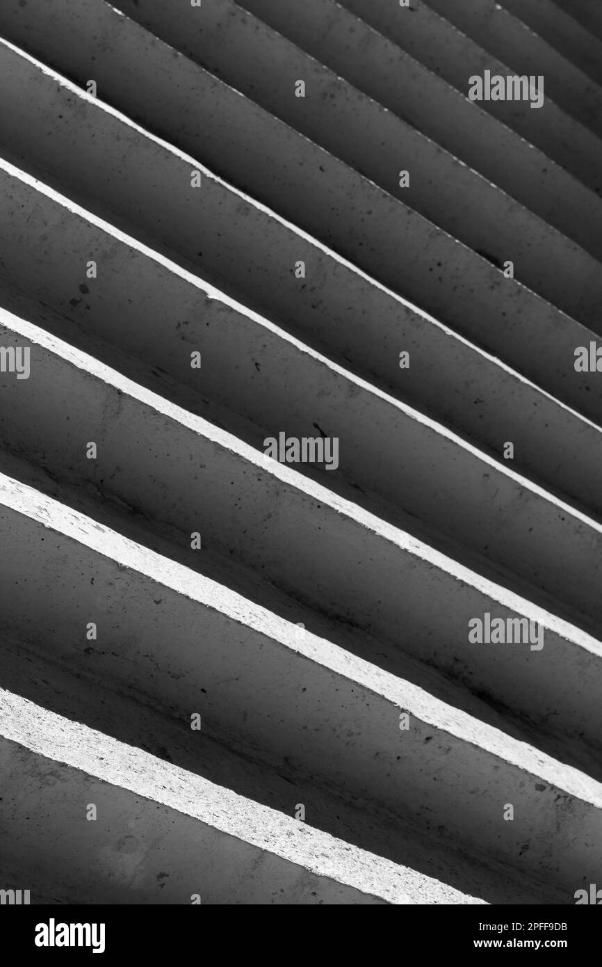 Escaliers en béton avec ombres profondes, arrière-plan architectural vertical abstrait. Photo en noir et blanc Banque D'Images