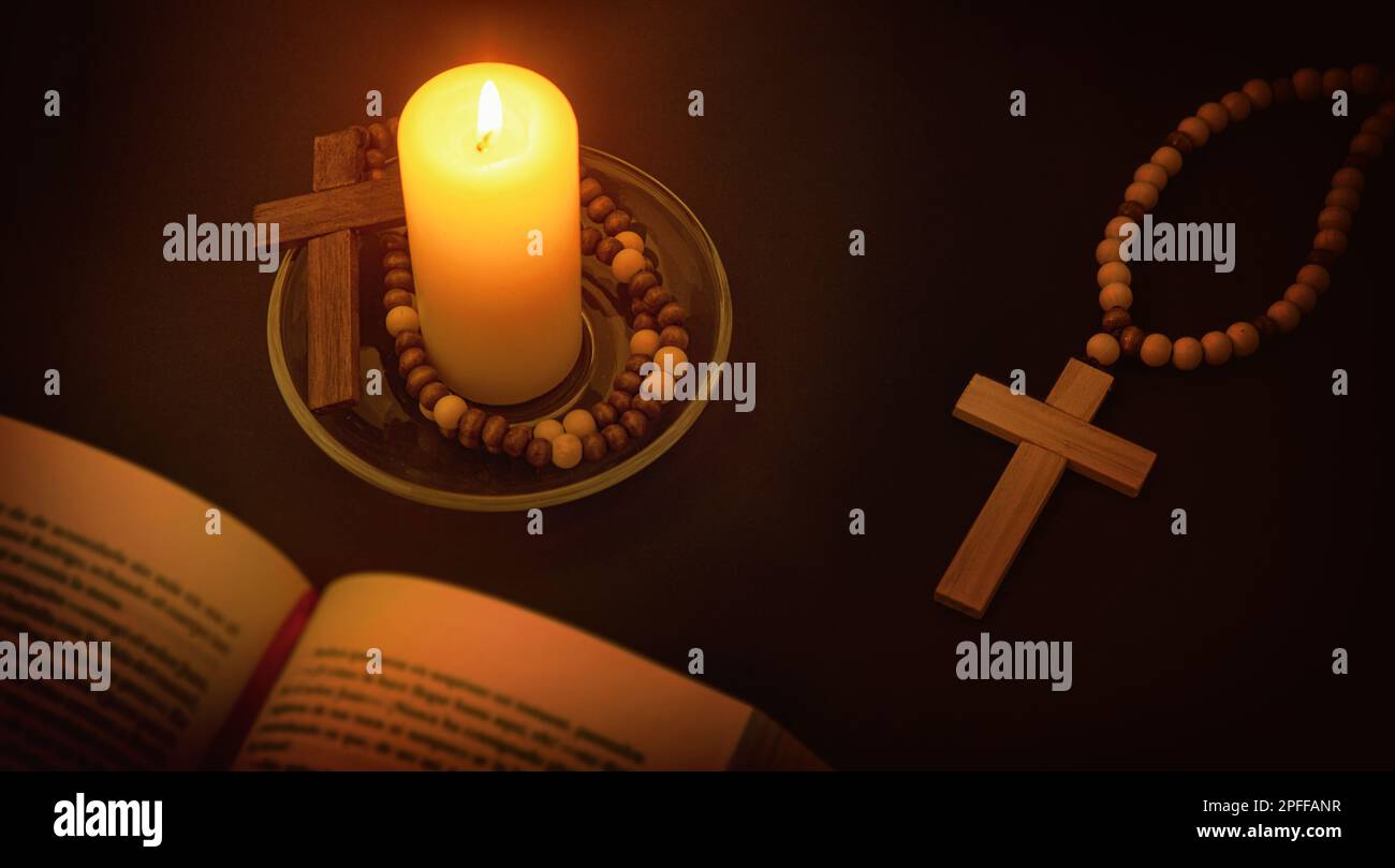 Environnement spirituel chrétien pour prier avec la bougie illuminant le symbole de la croix et de la bible sur table noire la nuit. Vue en hauteur du dessus. Banque D'Images