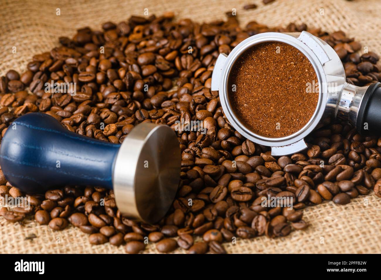 Une petite quantité de Marc de café dans un panier de porte-filtre et de grains de café déversés sur le fond Banque D'Images