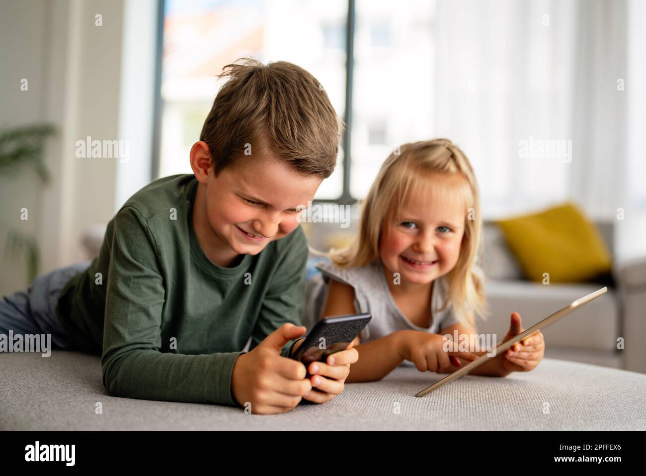 Petits enfants tenant un smartphone, tablette jouant au jeu mobile en ligne, enfant et gadget concept Banque D'Images