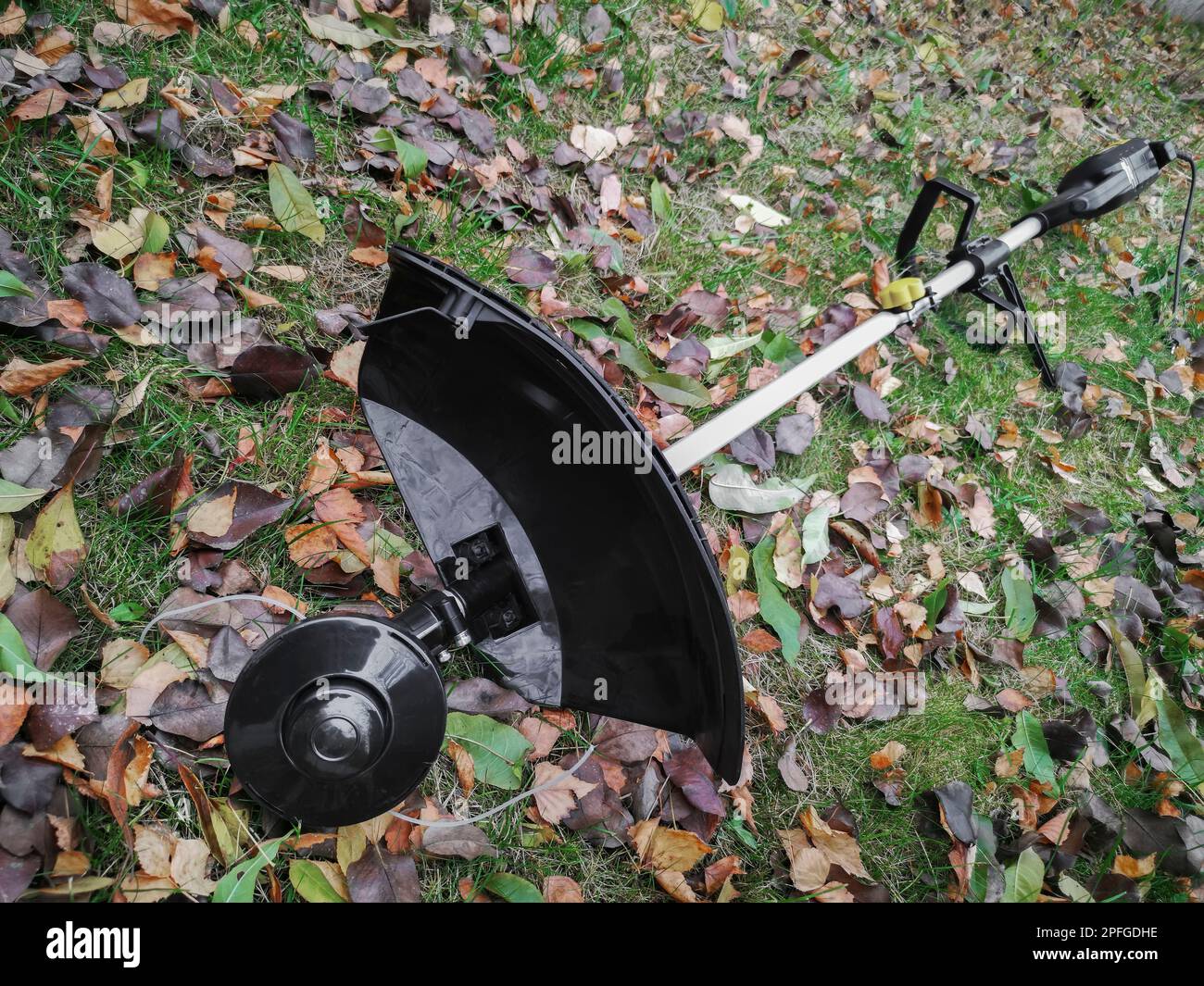 Appareils ménagers: Tondeuse-tondeuse pour tondre les pelouses . Présenté sur un fond d'herbe et de feuilles, vue de face, espace de copie Banque D'Images