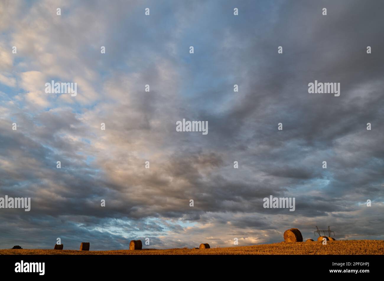 Ciel nuageux sur un champ avec des balles de paille Banque D'Images