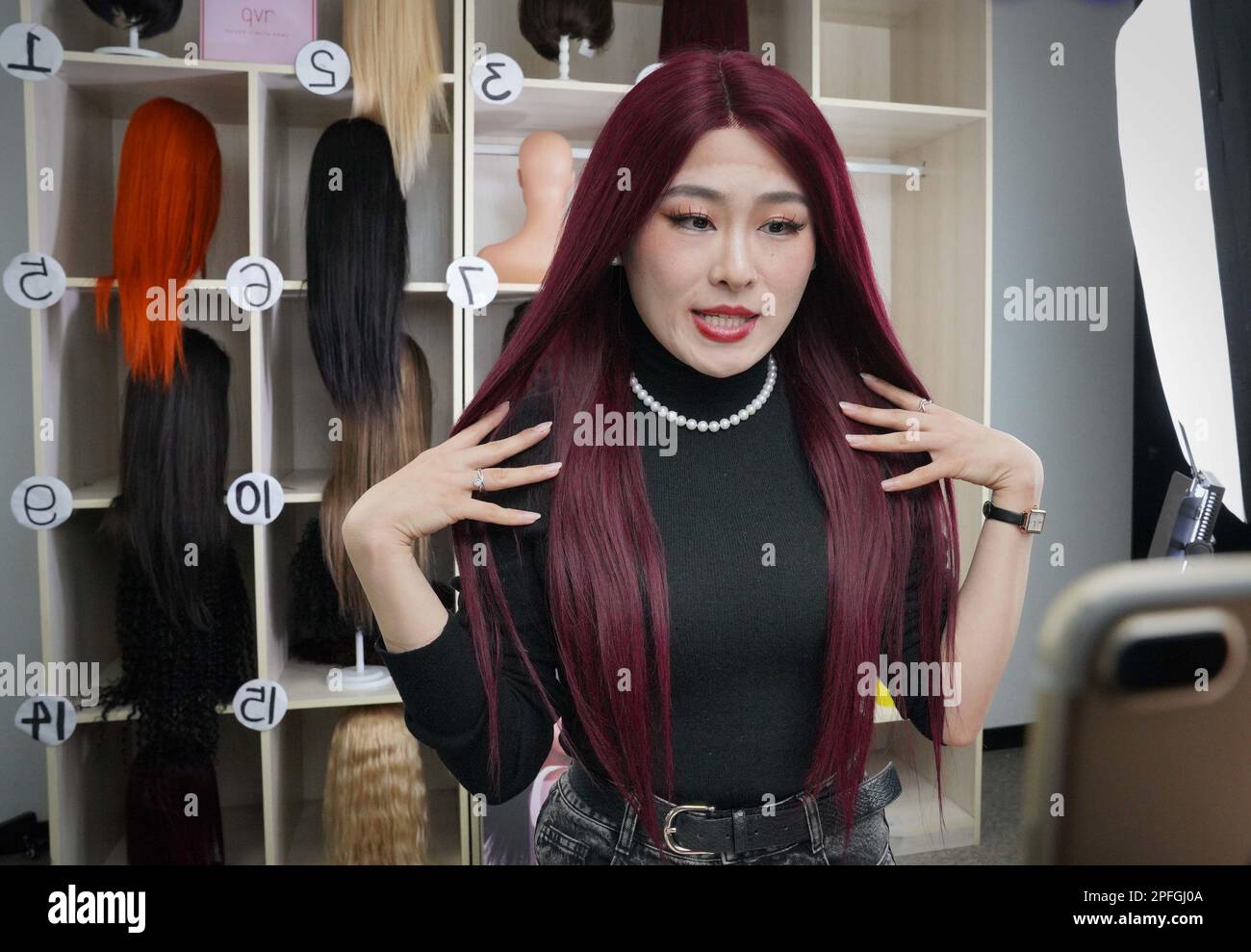 230317) -- XUCHANG, 17 mars 2023 (Xinhua) -- Un travailleur de Henan Henan  Rebecca Hair Products Co., Ltd présente une perruque en streaming dans la  ville de Xuchang, dans la province de