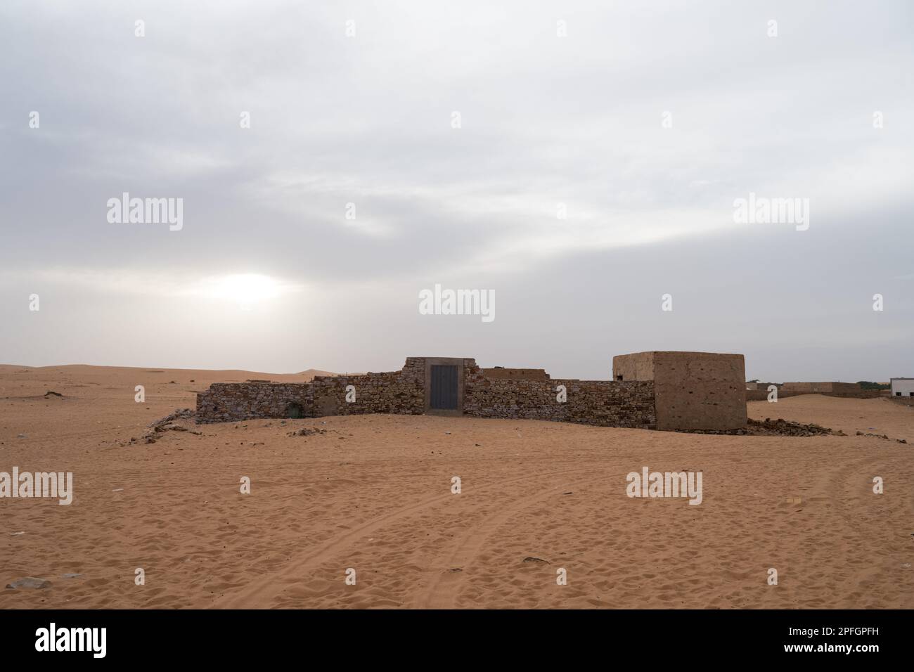 D'anciennes ruines de pierre se dressent au milieu des vastes dunes de sable du désert du Sahara dans la ville historique de Chinguetti, en Mauritanie. Banque D'Images