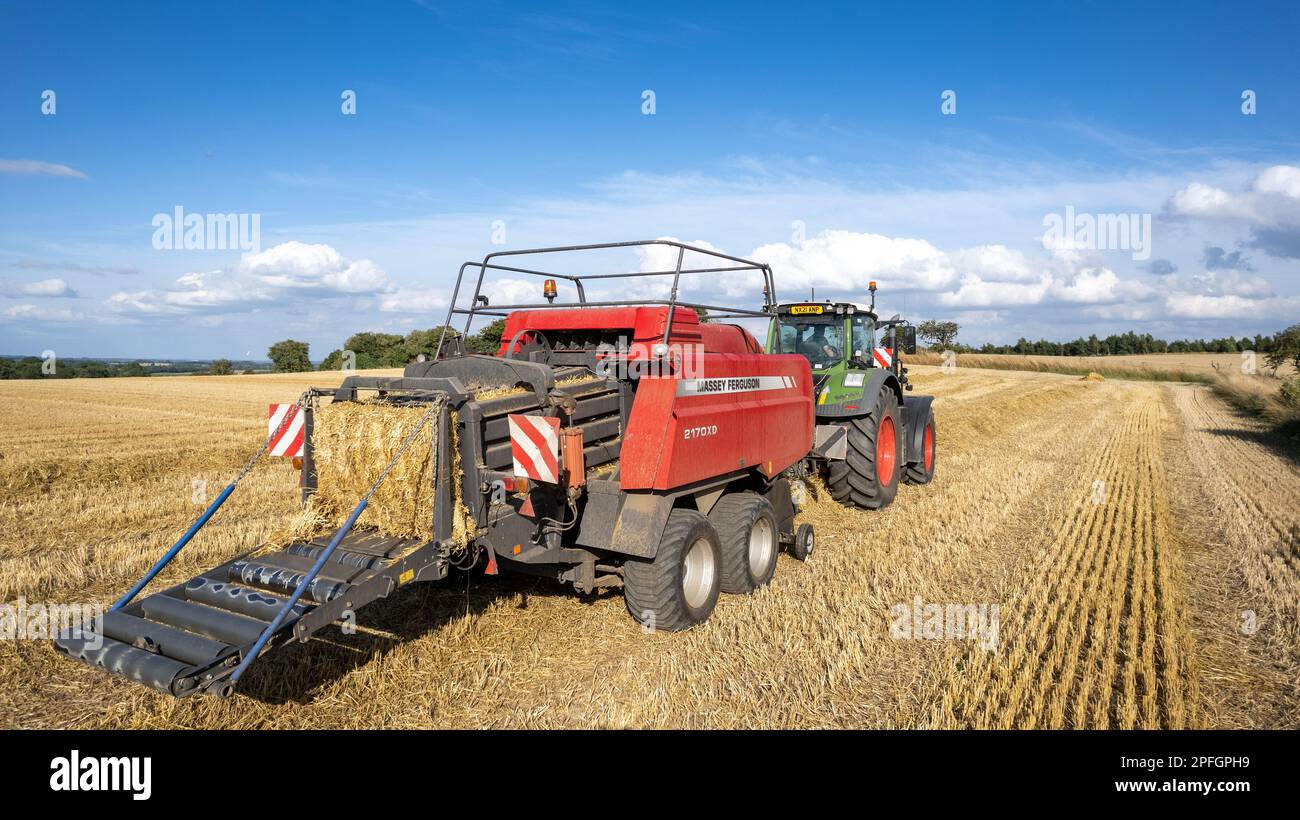Agriculteur qui a mis en balles de grosses balles de paille avec une presse à balles Massey Ferguson 2170XD et un tracteur Fendt, North Yorkshire, Royaume-Uni. Banque D'Images