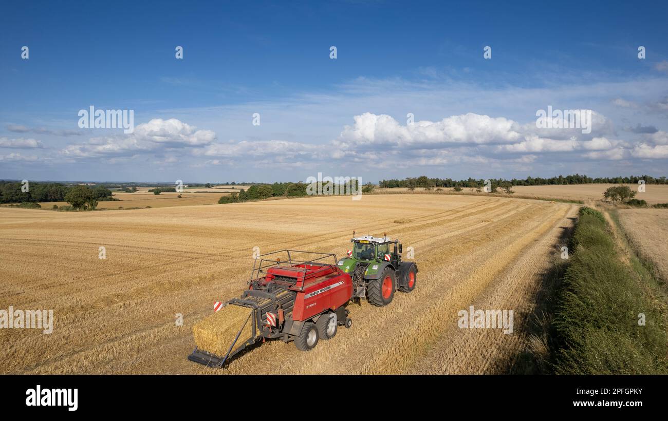 Agriculteur qui a mis en balles de grosses balles de paille avec une presse à balles Massey Ferguson 2170XD et un tracteur Fendt, North Yorkshire, Royaume-Uni. Banque D'Images