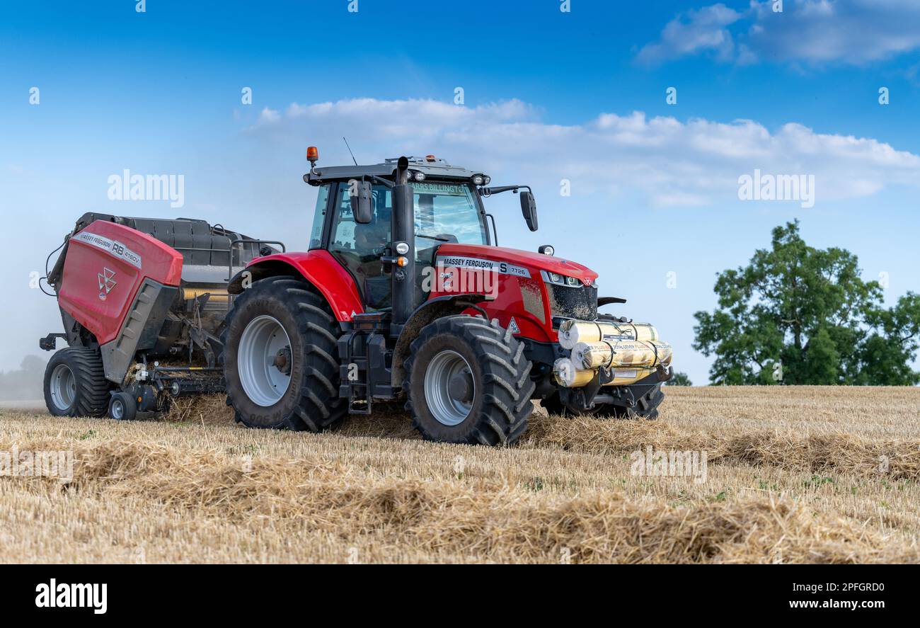 Pressage de paille en balles rondes avec un tracteur Massey Ferguson 7726 et une presse à balles RB4160v. La paille sera utilisée pour la litière des animaux. North Yorkshire, Royaume-Uni. Banque D'Images