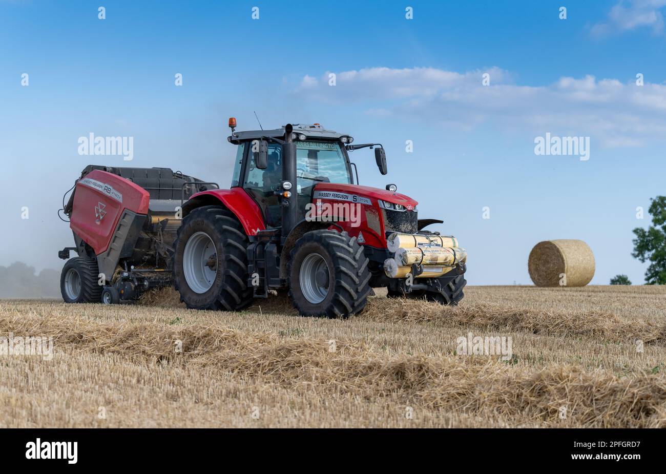 Pressage de paille en balles rondes avec un tracteur Massey Ferguson 7726 et une presse à balles RB4160v. La paille sera utilisée pour la litière des animaux. North Yorkshire, Royaume-Uni. Banque D'Images