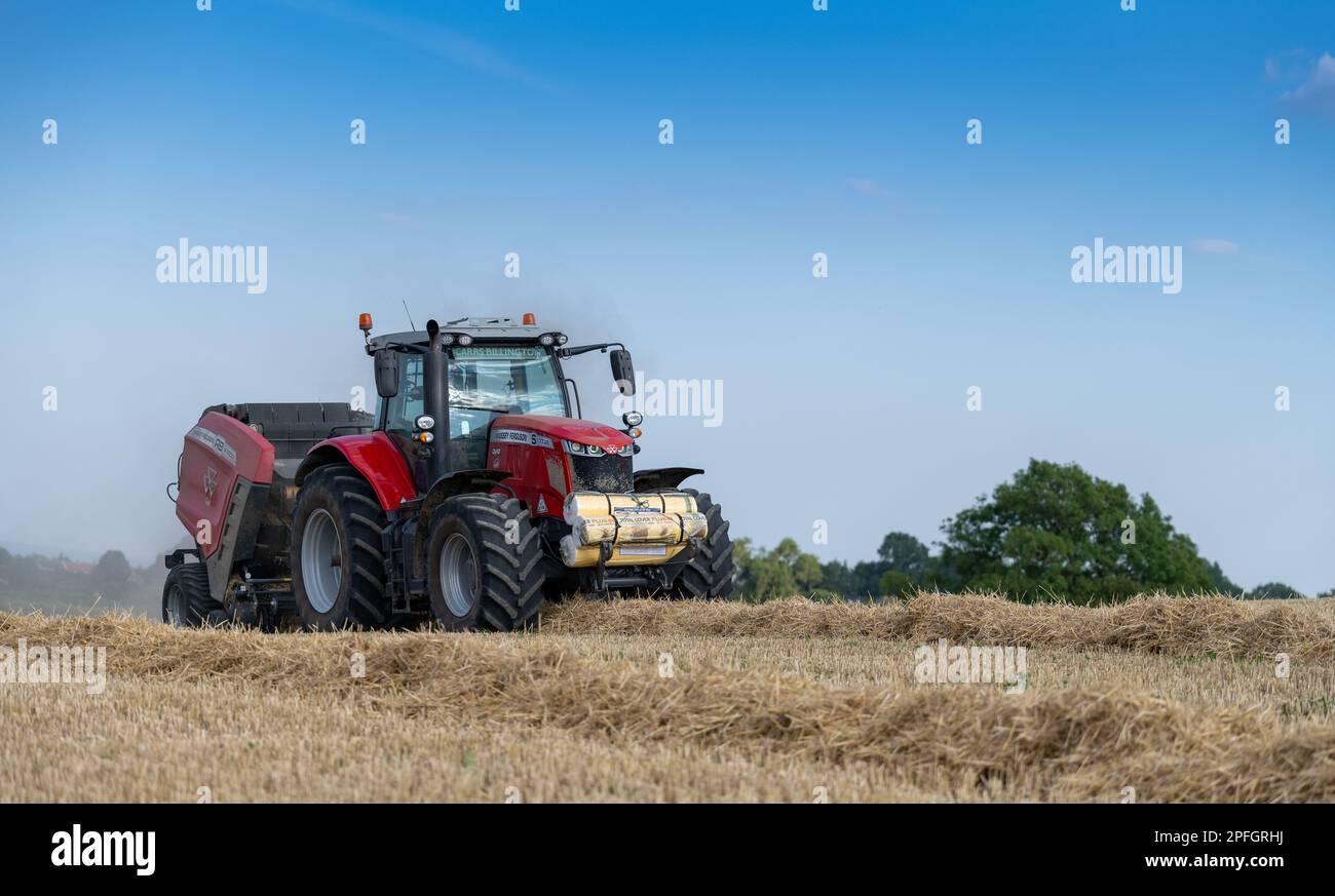 Pressage de paille en balles rondes avec un tracteur Massey Ferguson 7726 et une presse à balles RB4160v. La paille sera utilisée pour la litière des animaux. North Yorkshire, Royaume-Uni. Banque D'Images