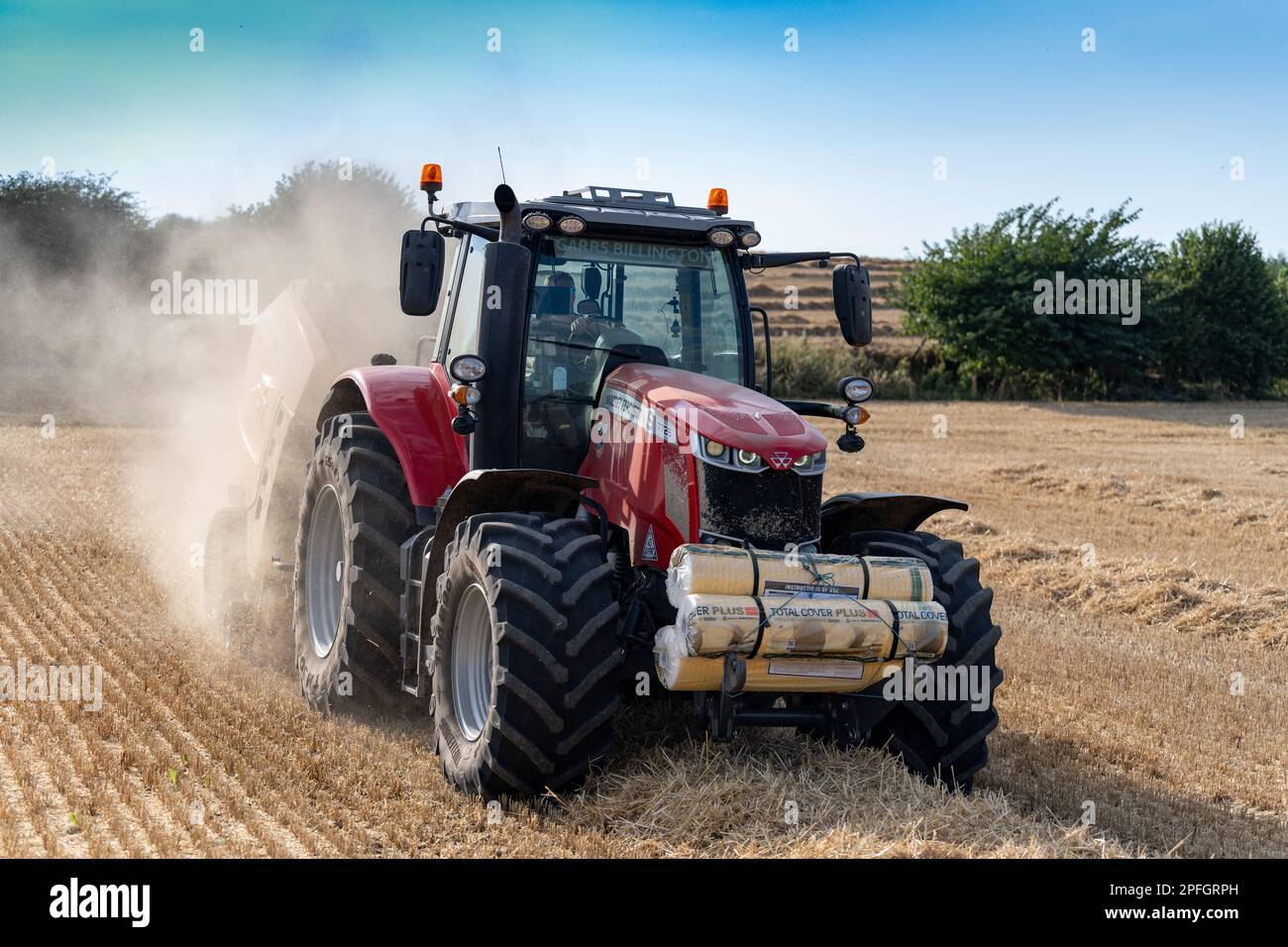Pressage de paille en balles rondes avec un tracteur Massey Ferguson 7726 et une presse à balles RB4160v. La paille sera utilisée pour la litière des animaux. North Yorkshire, Royaume-Uni. Banque D'Images