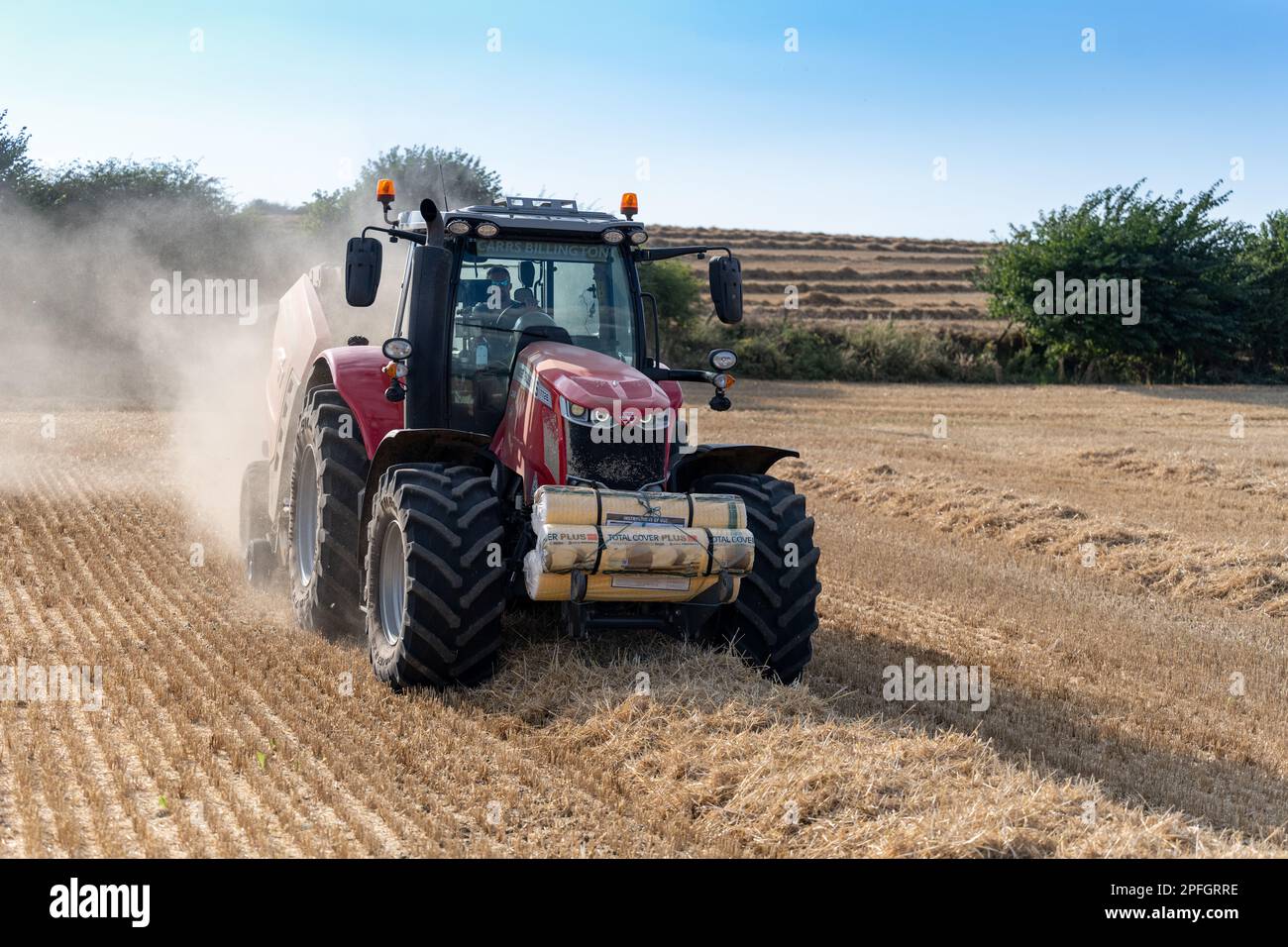 Pressage de paille en balles rondes avec un tracteur Massey Ferguson 7726 et une presse à balles RB4160v. La paille sera utilisée pour la litière des animaux. North Yorkshire, Royaume-Uni. Banque D'Images