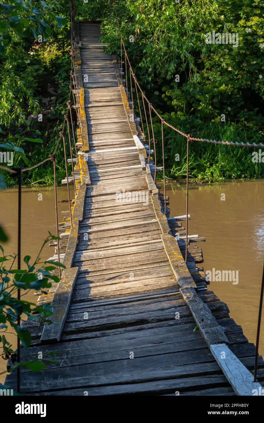 Pont suspendu en bois de l'autre côté de la rivière. Pont suspendu dans un petit village. Banque D'Images