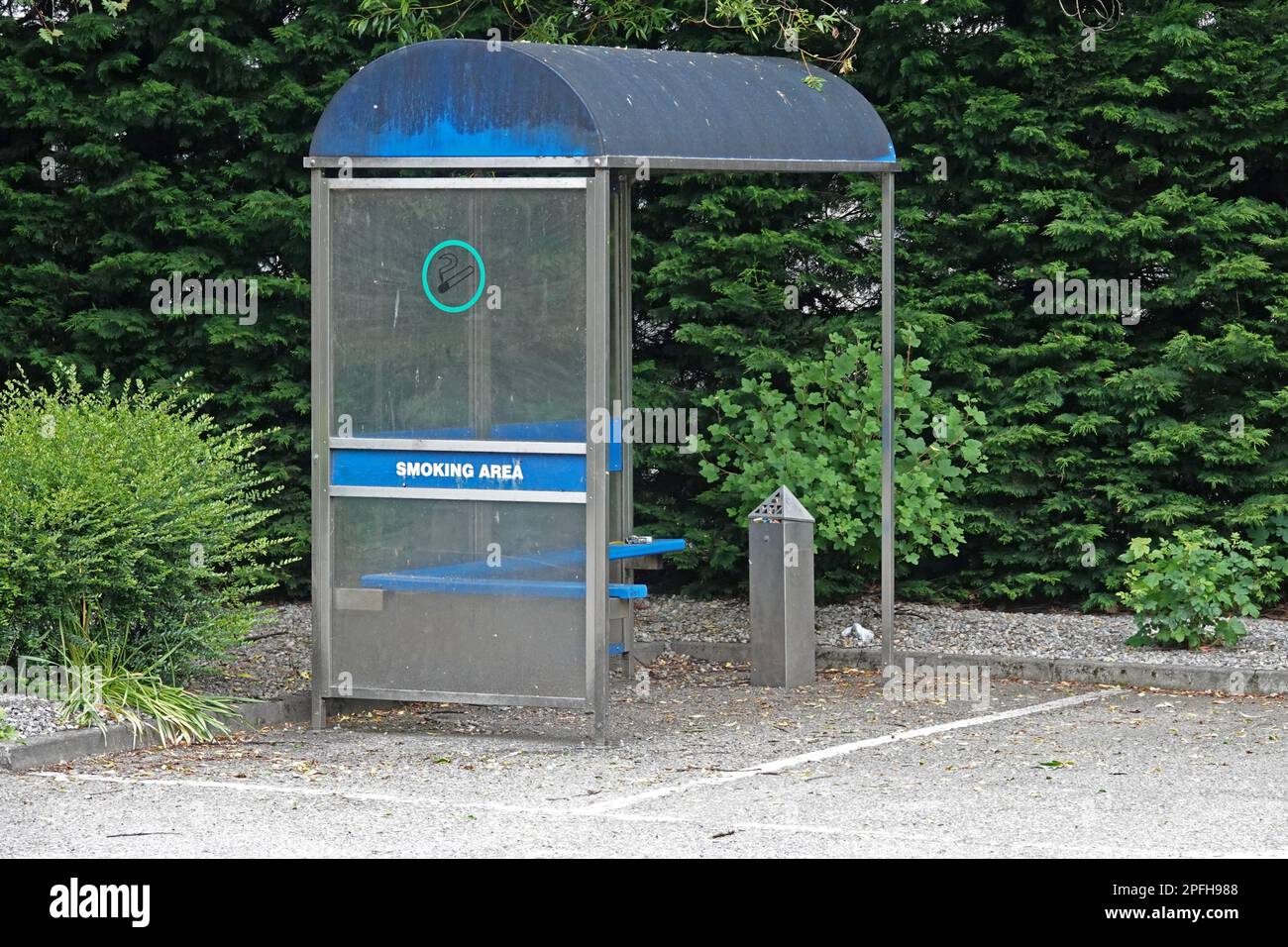 Une zone réservée à un abri pour fumeurs est affichée dans le coin d'un parking pendant la journée. Banque D'Images