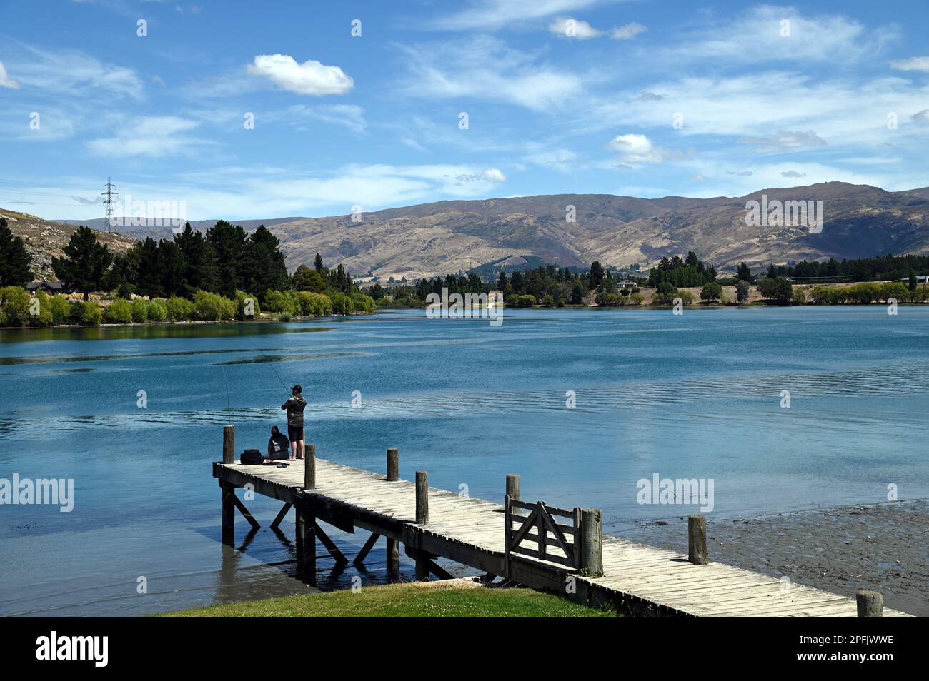 Deux personnes pêchent à partir d'une jetée au lac Dunstan, Cromwell, Central Otago. Le lac a été formé par le barrage de la centrale construit sur la rivière Clutha. Banque D'Images