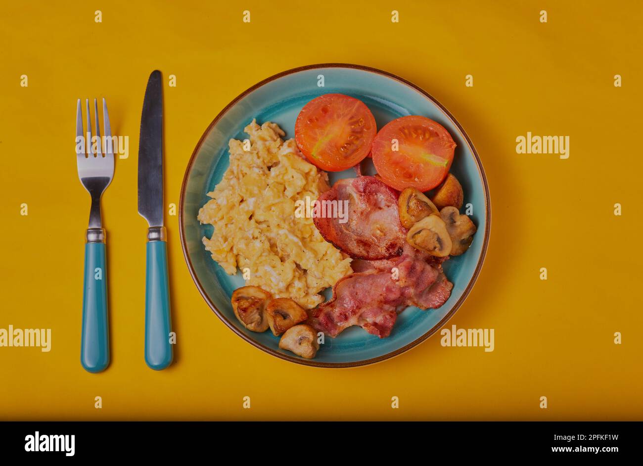 Petit déjeuner cuisiné avec œufs brouillés sur fond jaune. Banque D'Images