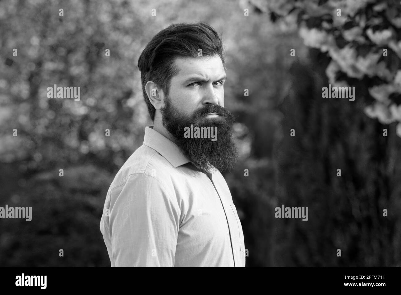 Homme hispanique réussi dans le jardin de printemps. Portrait d'un jeune homme beau, modèle de mode, avec la pensée formelle de coiffure dans le parc de printemps, portant Banque D'Images