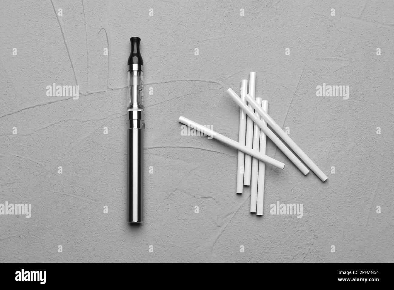 Cigarettes et dispositif de vapotage sur une table grise, posé à plat. Alternative fumeurs Banque D'Images