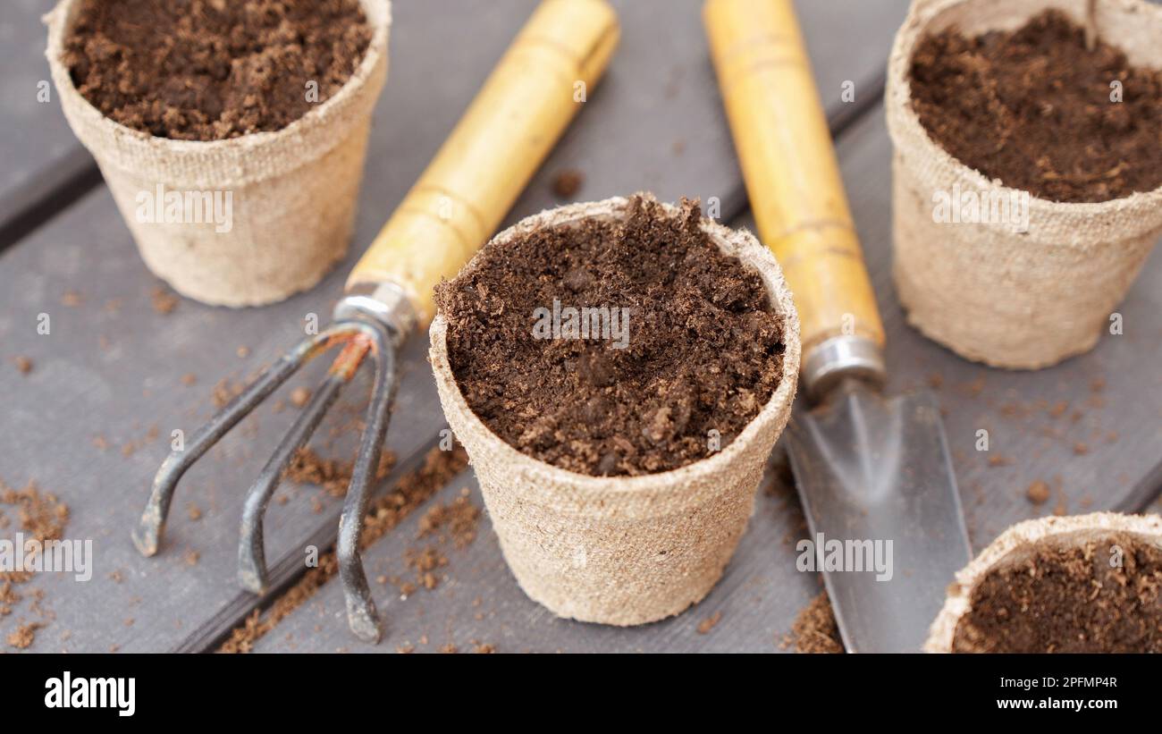 Gros plan de pots de tourbe biodégradables et d'outils de jardin écologiques, vue de dessus, mise au point sélective. Jardinage naturel de printemps, éco, soin des plantes, produ biologique Banque D'Images