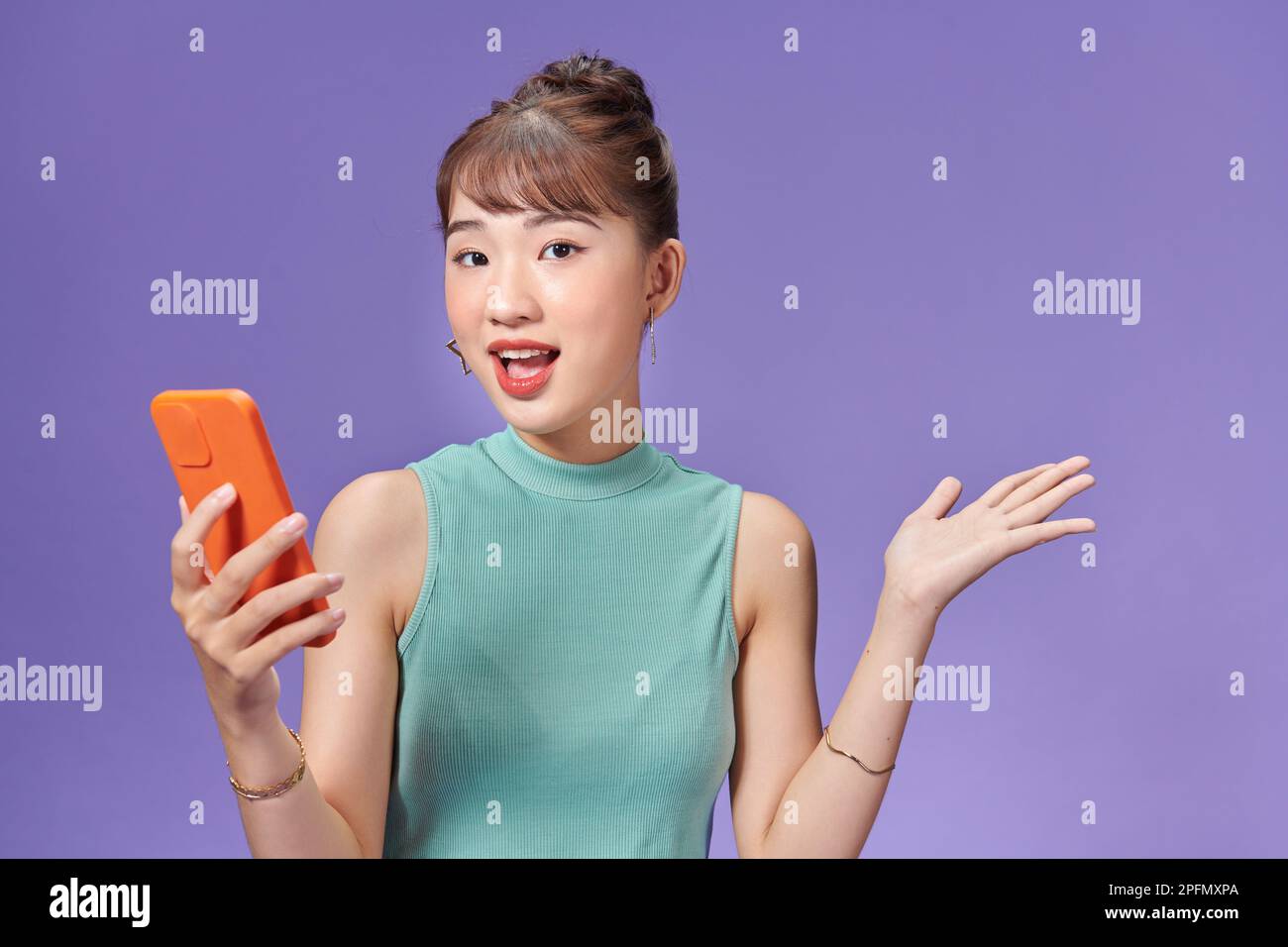 Jeune femme asiatique tenant son téléphone et regardant avec enthousiasme Banque D'Images