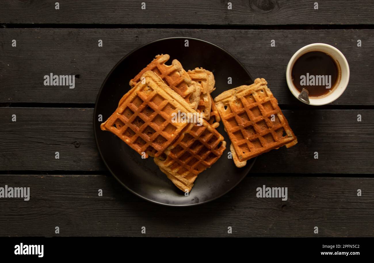 Gaufres viennoises sur une table en bois et une tasse avec café, gaufres pour le petit déjeuner dans la cuisine de la maison Banque D'Images