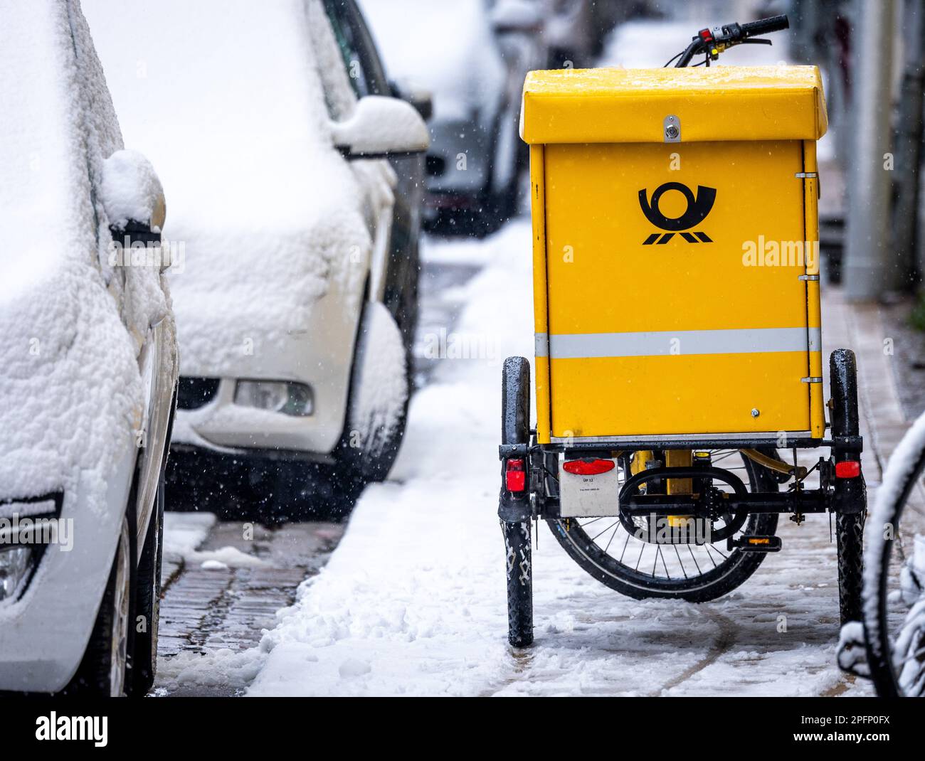Schwerin, Allemagne. 10th mars 2023. Un vélo de transport de lettres est stationné sur le trottoir de la vieille ville en forte chute de neige. Sur 10 mars 2023, commence le quatrième cycle de négociations dans le conflit de négociation collective à Deutsche Post. Il s'agit d'une nouvelle convention collective pour environ 160 000 salariés de la division Post & Parcel Allemagne. Verdi exige 15 pour cent de plus d'argent. Credit: Jens Büttner/dpa/Alay Live News Banque D'Images